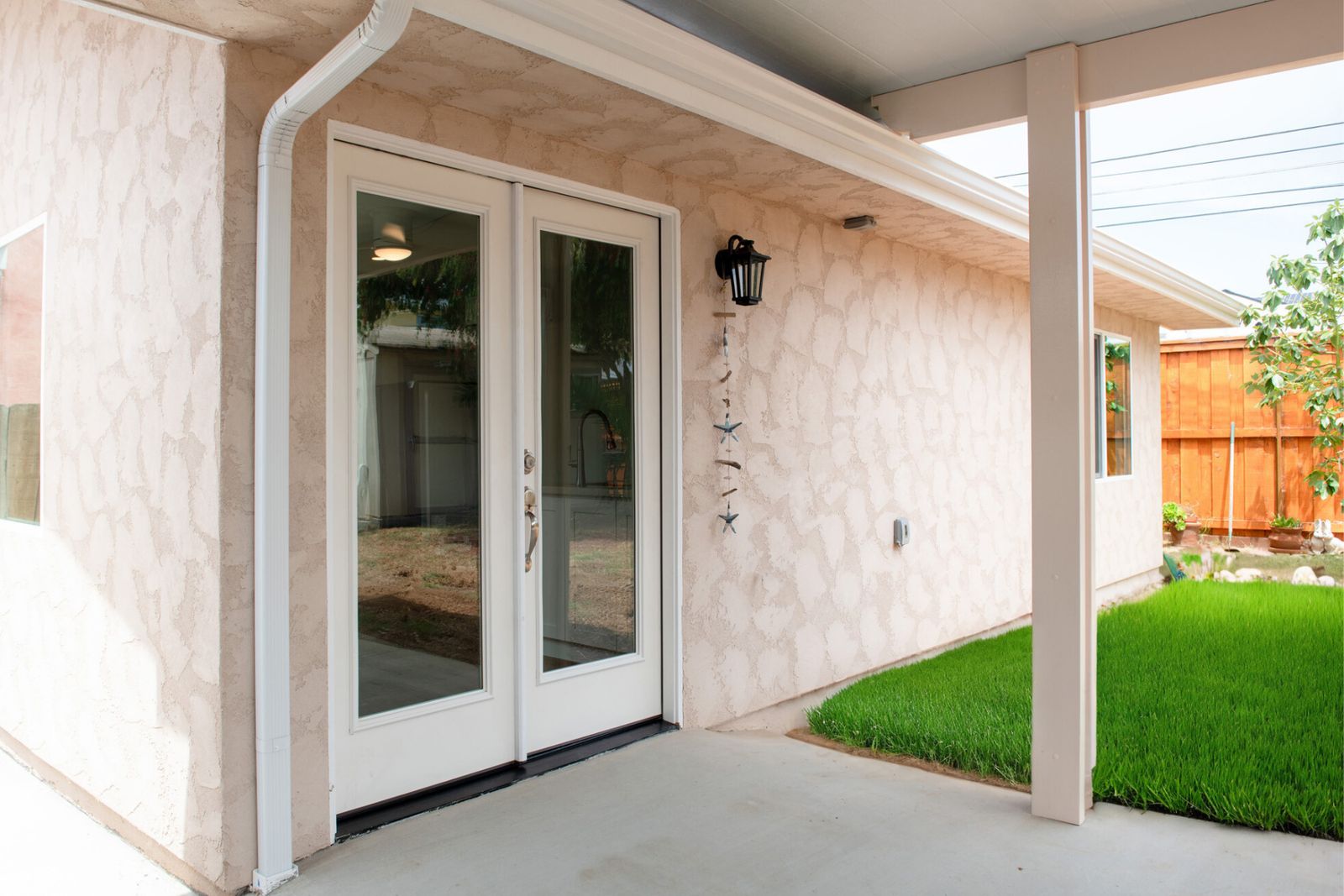 Imperial Beach ADU patio with white French doors, a lantern and a strip of lawn