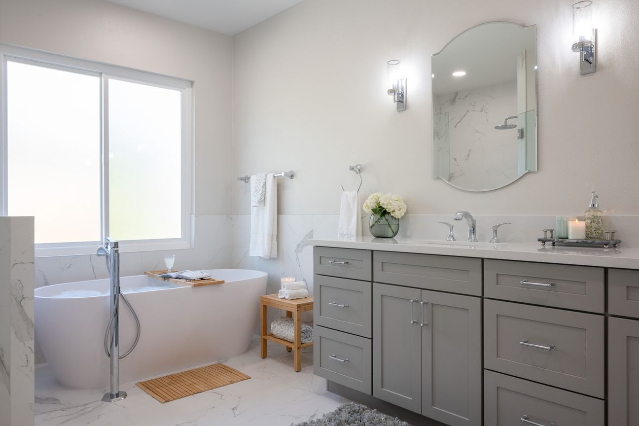Poway transitional bathroom remodel with a grey double vanity, a freestanding tub and arched mirrors