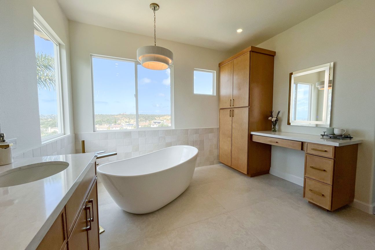 Carmel Valley primary bathroom remodel with a freestanding tub, a maple vanity, a makeup vanity and a linen tower