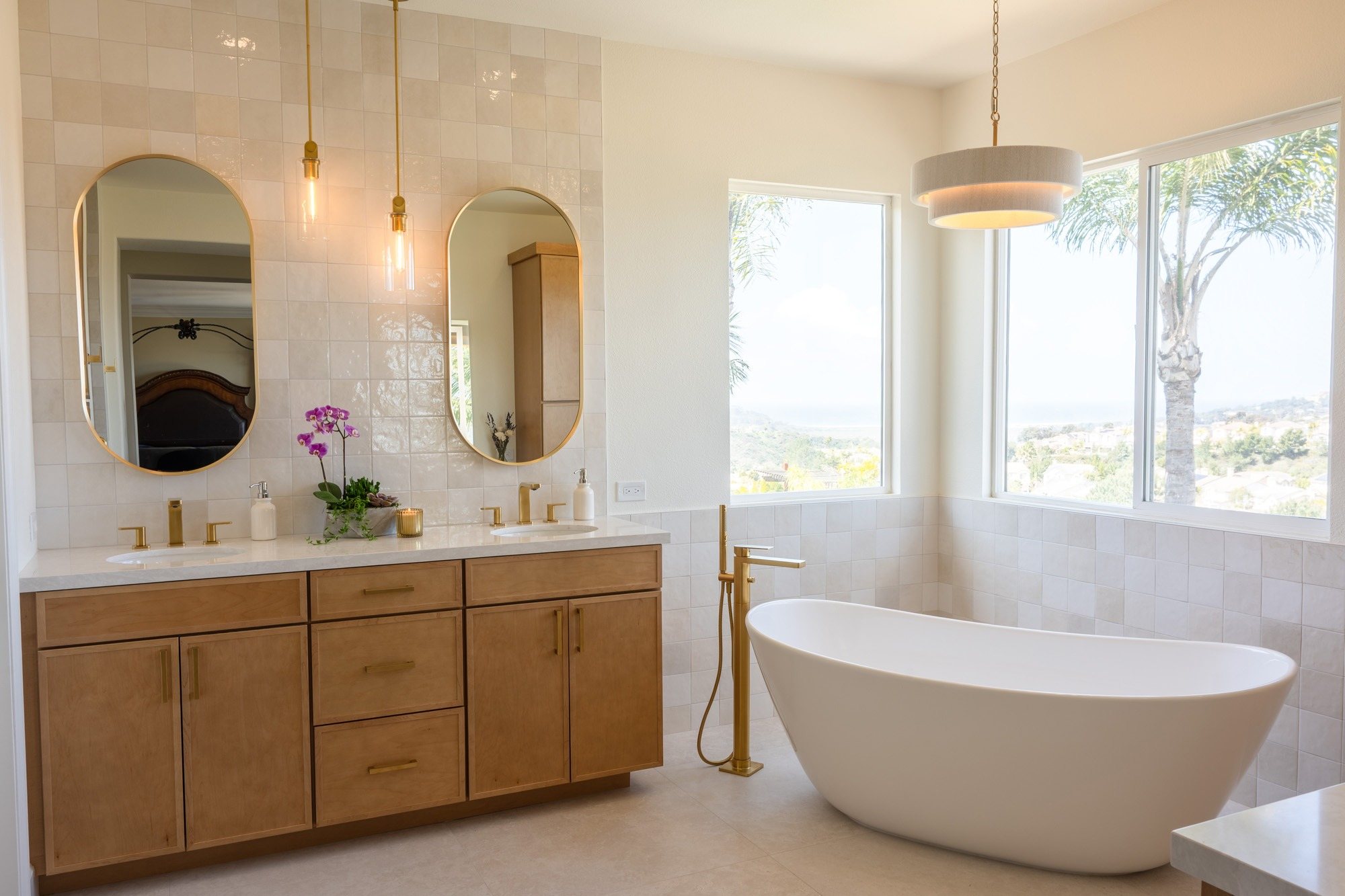 Carmel Valley primary bathroom remodel with a freestanding tub under the window, a maple double vanity, brass fixtures and zellige tile