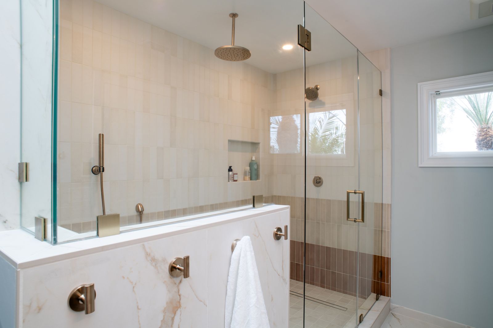 A Del Mar walk-in shower with a bench, a niche and a linear drain behind frameless glass