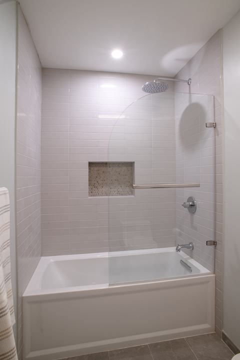 Alcove tub with a curved frameless glass panel that swings clear of the opening