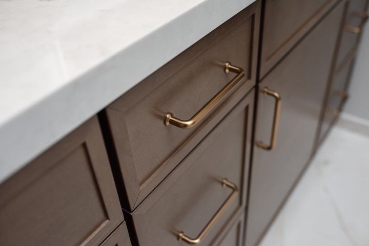 Brass bar pull on a Maple Latte drawer front below the quartz countertop edge