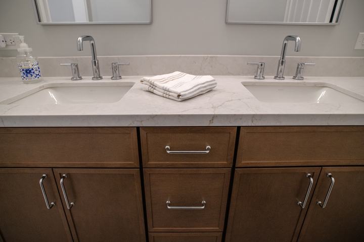 Two chrome faucets and undermount sinks set into the quartz counter, folded towels between