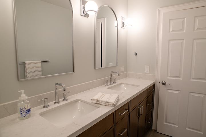 The vanity run from the far end, arched mirrors and globe sconces along the wall