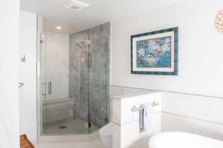 Glass-enclosed walk-in shower with blue-gray accent tile and marble-look wall tile