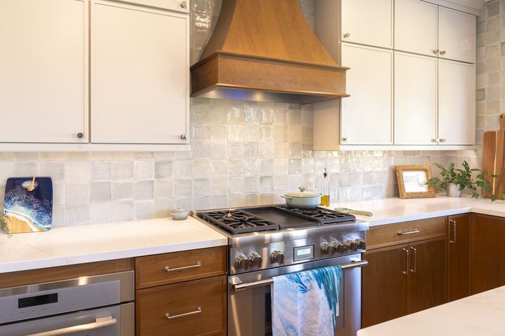Thermador ProHarmony gas range beneath custom wood hood with glossy Marin ceramic tile and two-tone cabinetry