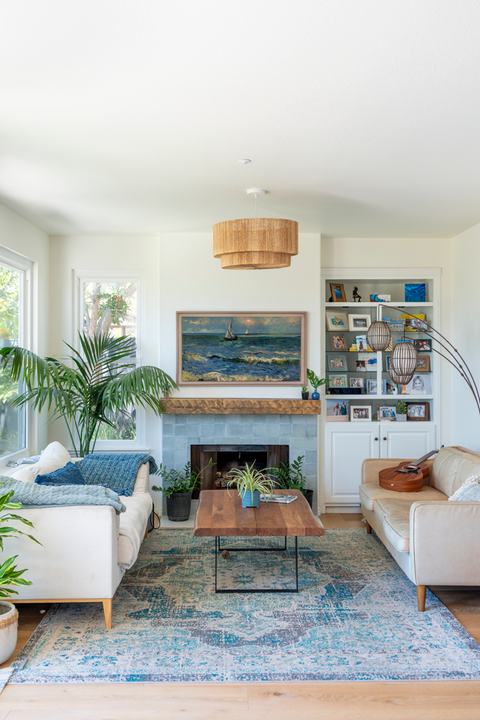 Adjacent family room with coastal fireplace surround, built-ins, woven pendant, and layered blue accents