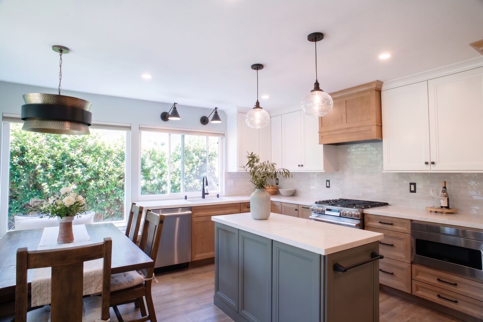 Kitchen with a green island, maple cabinetry, and white uppers beside the banquette table