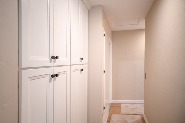 Tall white shaker pantry cabinets with square bronze knobs beside the kitchen