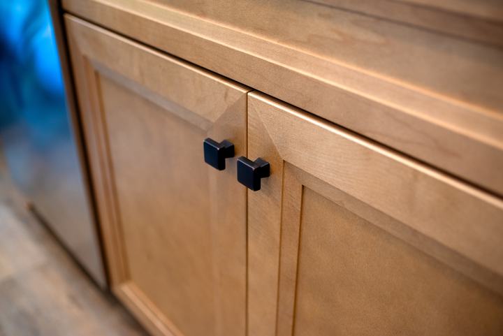 Two bronze knobs on maple shaker doors below a drawer front