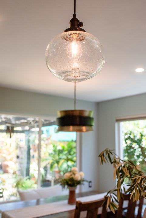 Glass globe pendant in the foreground with the banquette drum pendant behind