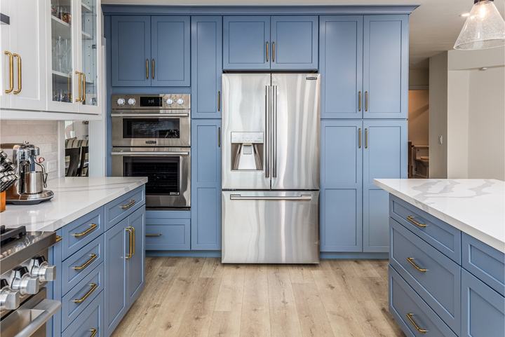 Built-in fridge flanked by tall blue pantry cabinets