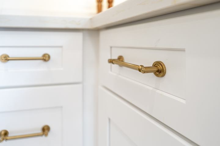 Brass drawer pulls detail on white Shaker base cabinets