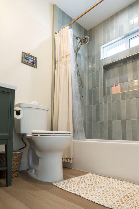 Guest bath tub, shower with vertical sea-green tile and niche