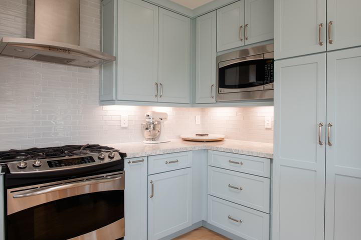 Tall pantry cabinetry and built-in microwave with blue cabinet finish and quartz countertop