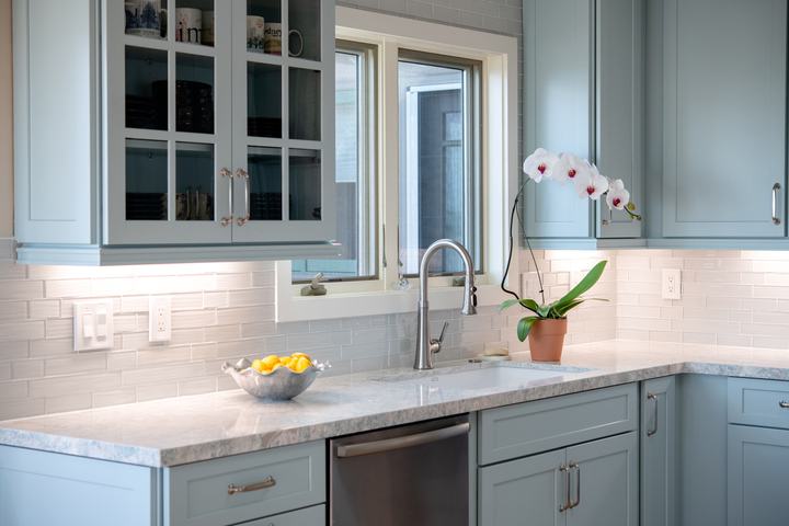 Sink wall with blue cabinets, dishwasher, quartz counters, and white mosaic backsplash