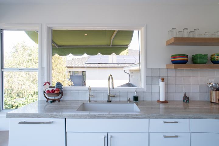 Undermount sink with pull-down and beverage faucets beneath a window, square glazed tile around it