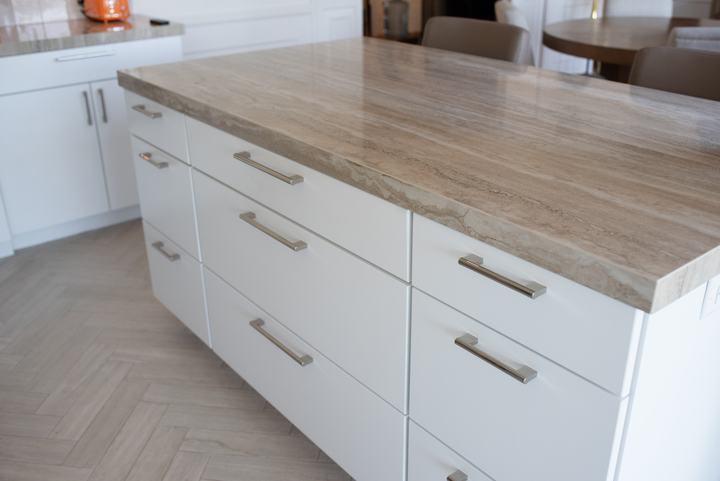 Stacked island drawers with long pulls under a thick veined porcelain edge