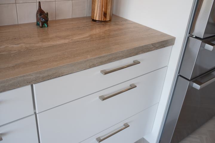 Corner of the porcelain countertop over white drawers next to the refrigerator