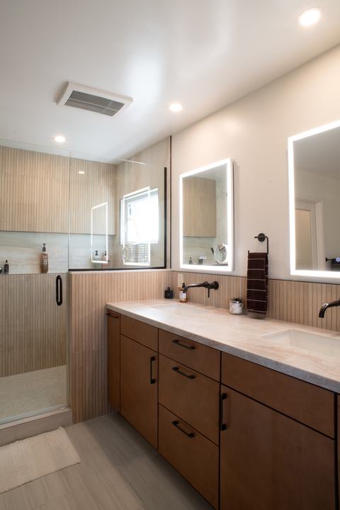 Maple vanity and glass shower panel under recessed lights and a ceiling exhaust fan