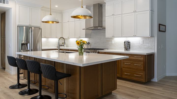 Wide view of Poway kitchen remodel with quartz-top walnut island, white shaker uppers, brass dome pendants, and wood floors