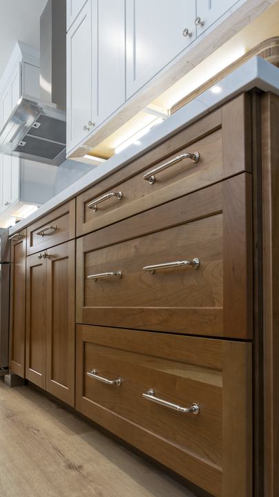 Low-angle detail of walnut drawer fronts with polished-chrome pulls and soft under-cabinet LED lighting