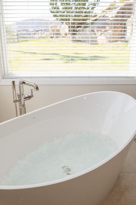Hydrotherapy bubbles churning in BainUltra tub while hillside scenery is visible through the window.