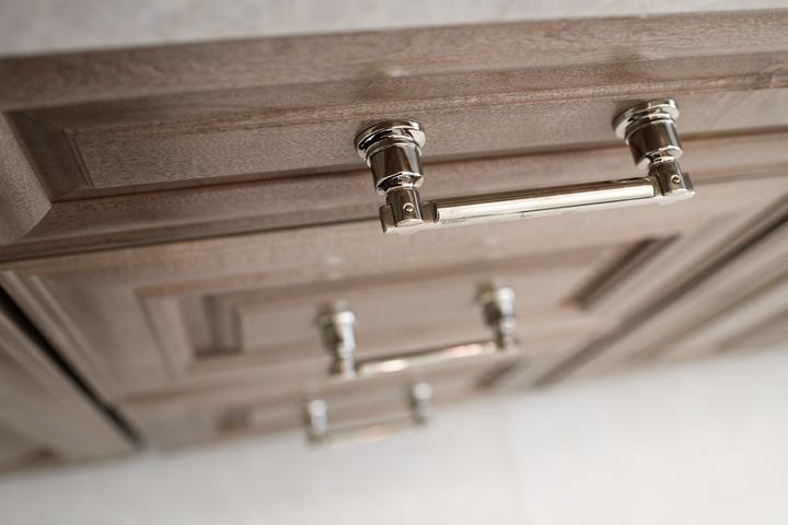 Angled detail of polished-nickel appliance pull on custom maple drawer front in the luxury vanity.