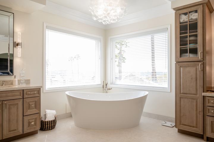 Freestanding oval soaking tub nestled in a windowed corner beneath a glowing glass-bubble chandelier.