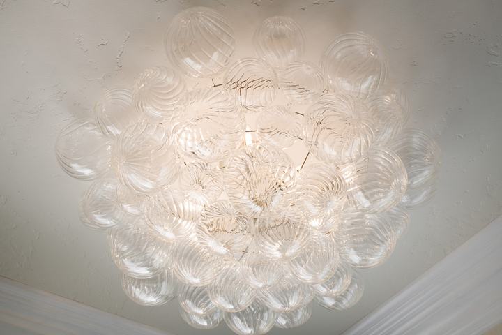 Bubble chandelier centered on cove ceiling in the luxurious primary bath.
