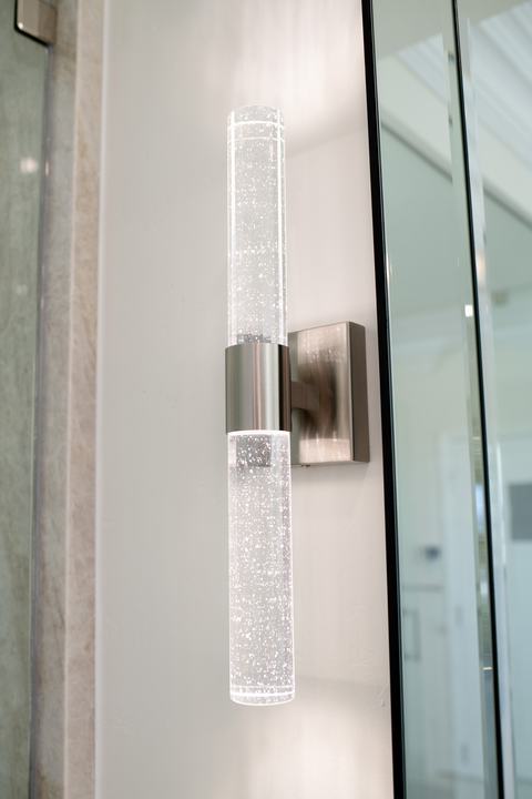 Sparkling crystal-rod wall sconce providing ambient lighting by the vanity mirror.