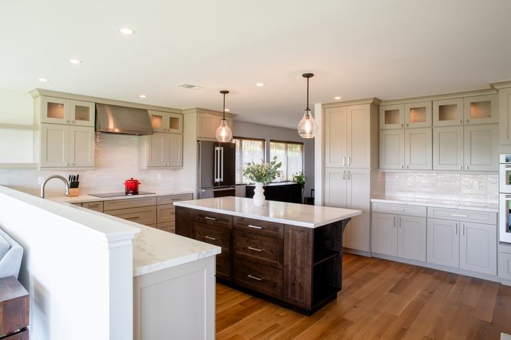 Open kitchen with dark alder island, oatmeal cabinets, and white countertops