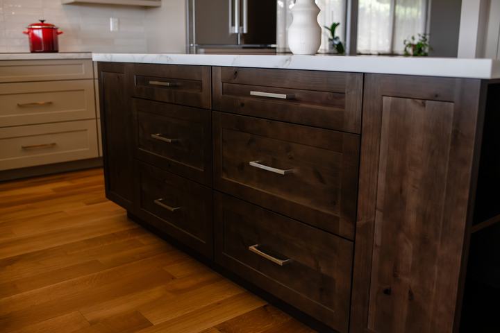 Stained knotty alder kitchen island with white countertop and warm wood flooring