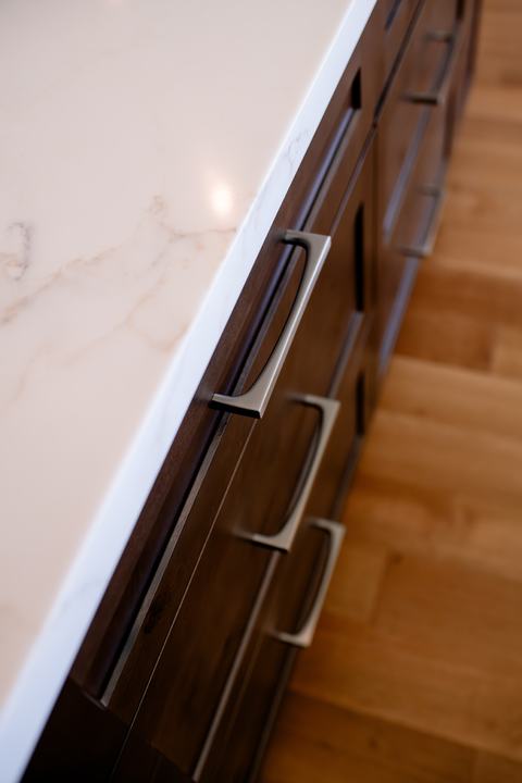 Close-up of stained knotty alder island drawers with brushed metal pulls
