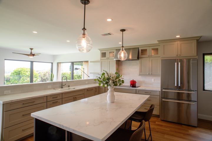 Kitchen island with Calacatta-style countertop, pendant lights, and custom cabinetry