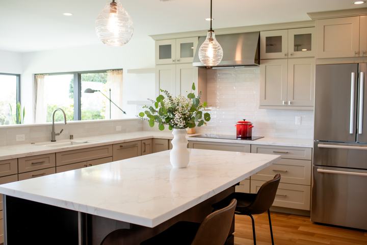 Large kitchen island with pendant lights and oatmeal cabinets