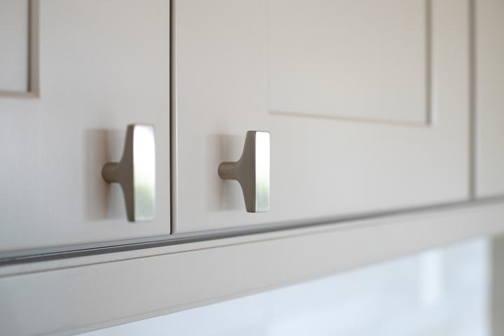 Close-up of brushed hardware on white upper kitchen cabinets