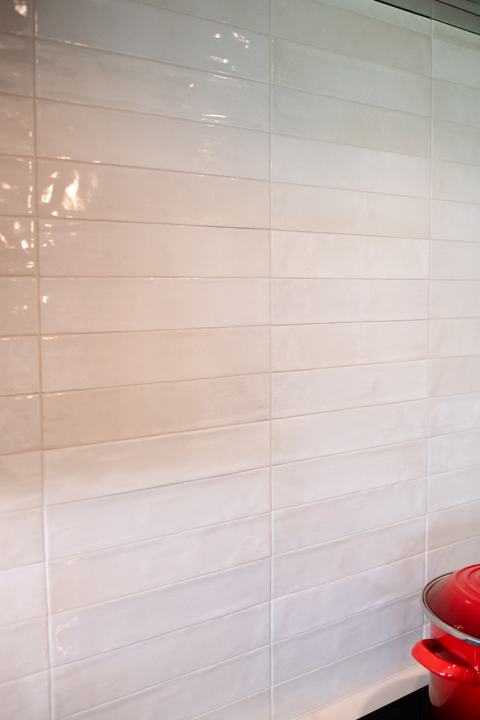 Glossy white Celine porcelain backsplash tile behind the induction cooktop