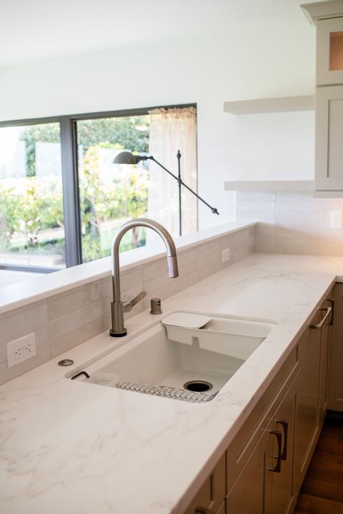 Kitchen sink and Delta pull-down faucet with bright countertop and backsplash