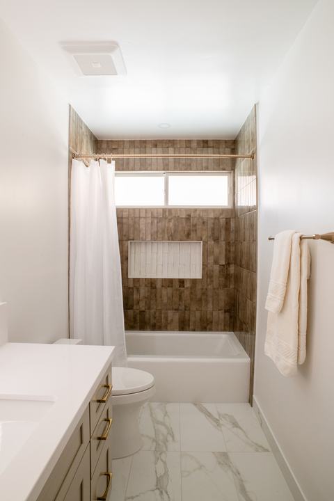 Hall bathroom remodel with brown gloss shower tile and white niche
