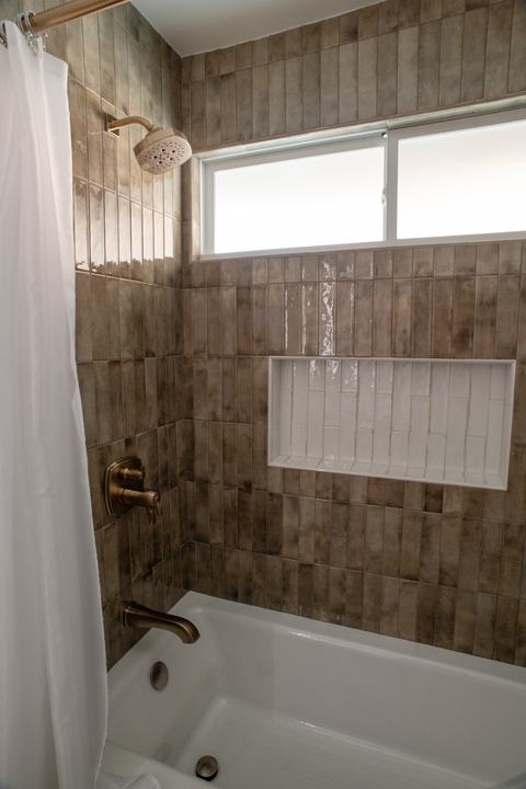 Close-up of bath shower with Delta fixtures and white tile niche