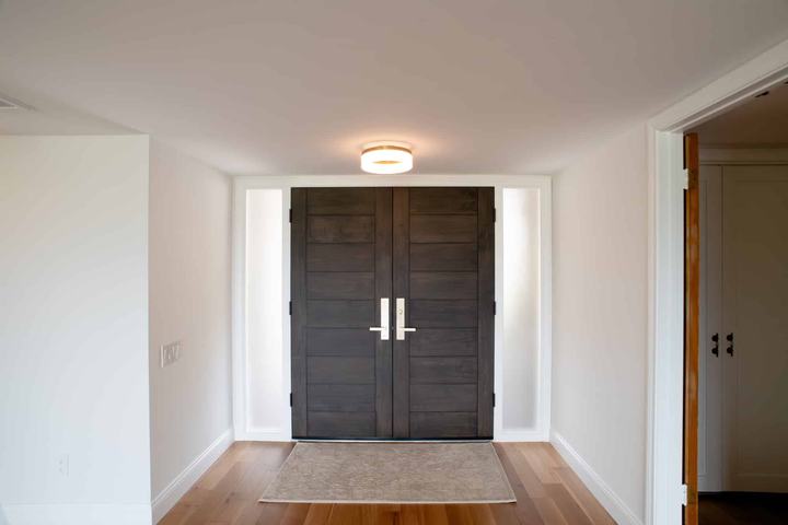 Closed dark wood double entry doors with sidelights and white oak flooring