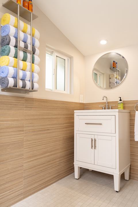 Pool bath vanity with round mirror and striped wainscot