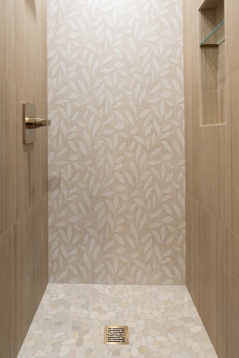 Pebble shower floor meeting a leaf-pattern feature wall in the downstairs bath