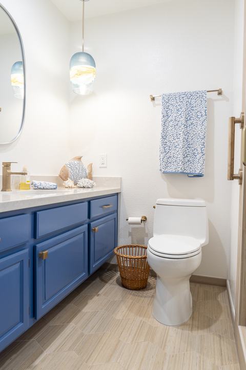 Vanity and toilet with coastal glass pendant and warm brass accessories
